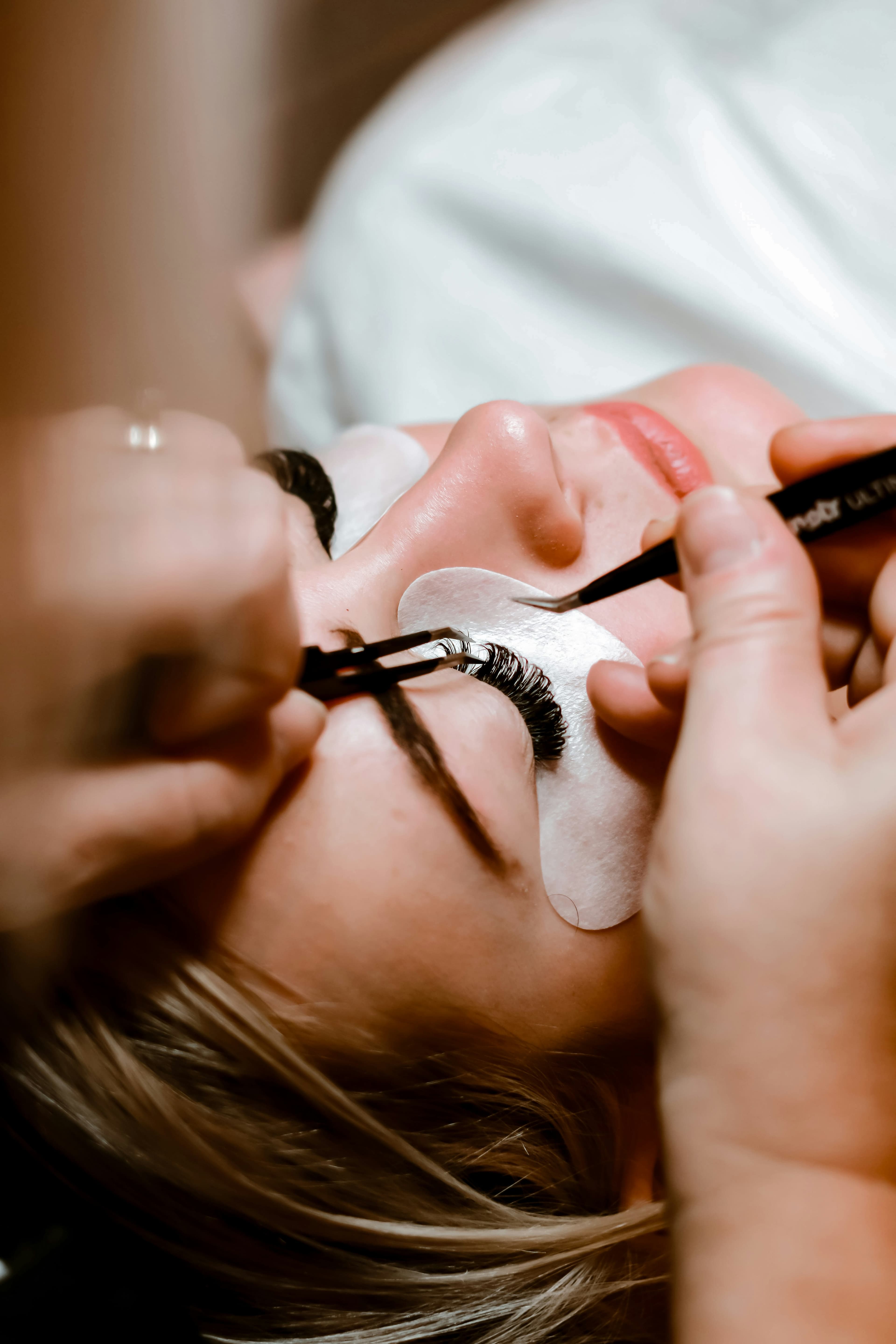 Lash artist applying individual eyelash extensions with tweezers